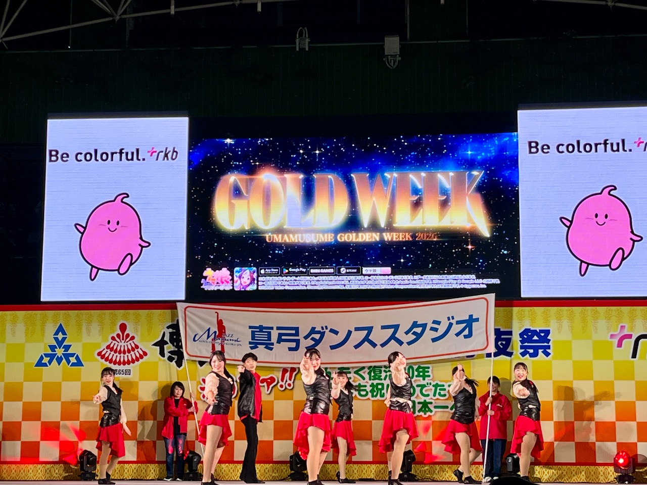 前夜祭inお祭り本舞台　横断幕の前で観客席に向かって指差しポーズ