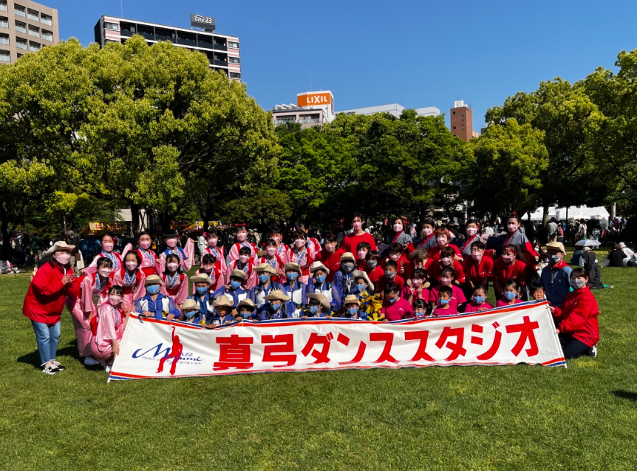 真弓ダンススタジオの横断幕の前で様々な衣装で並んでいます