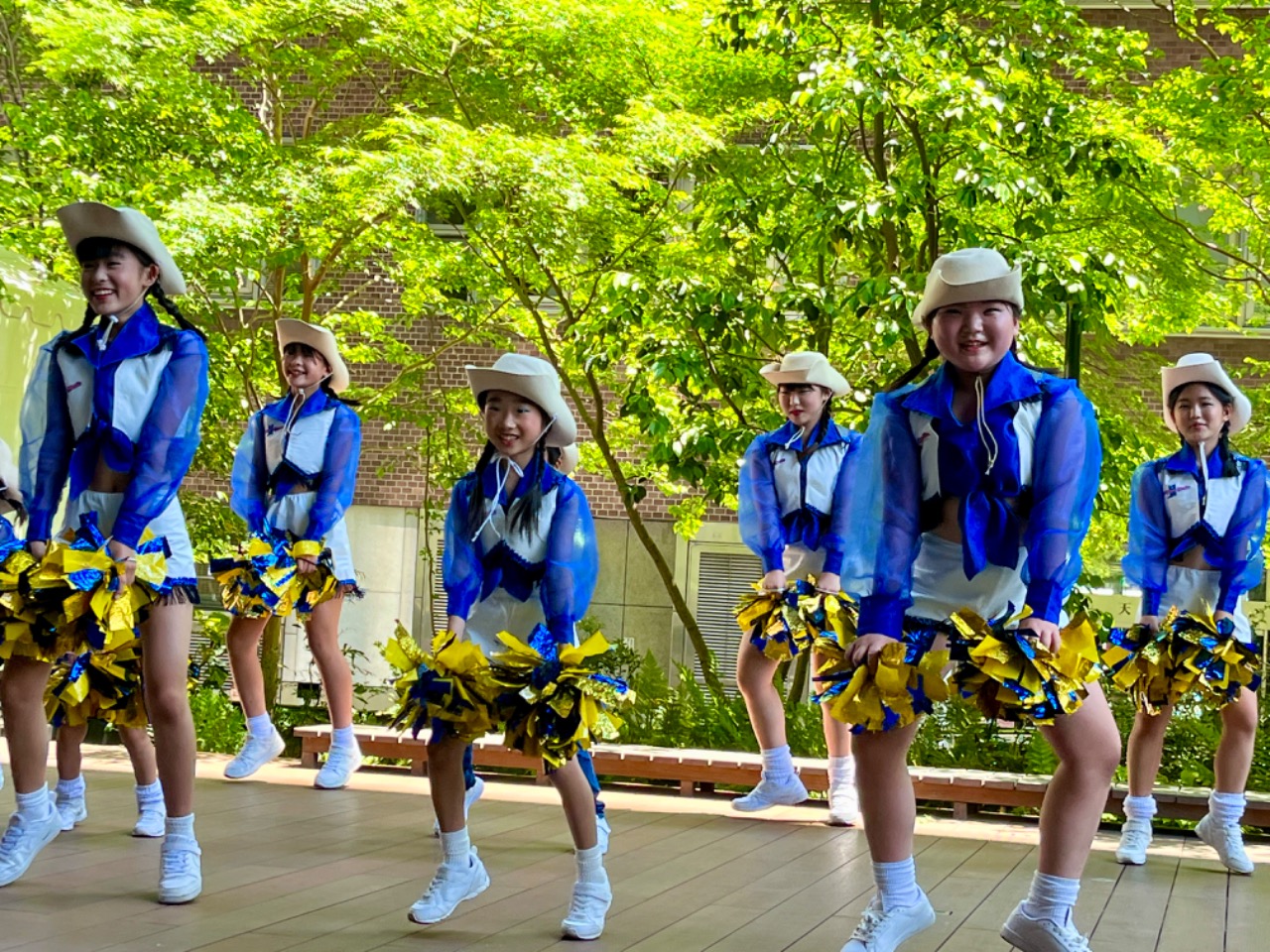 ふくぎんどんたくステージで幼児小学生がポンポンを両手に持って足でリズムを刻んでいます