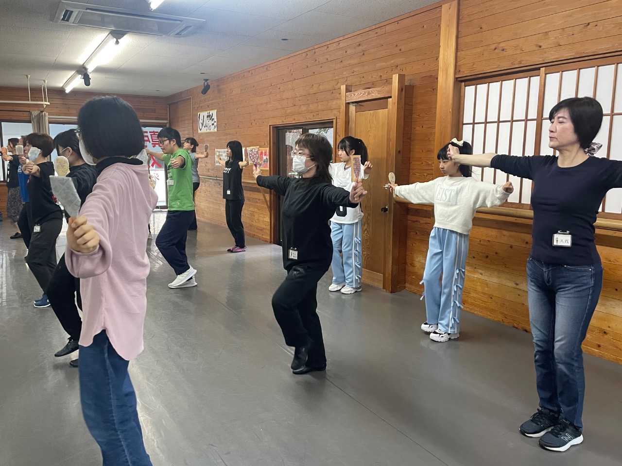 練習スタジオに両腕を広げて並び振付の練習をしています