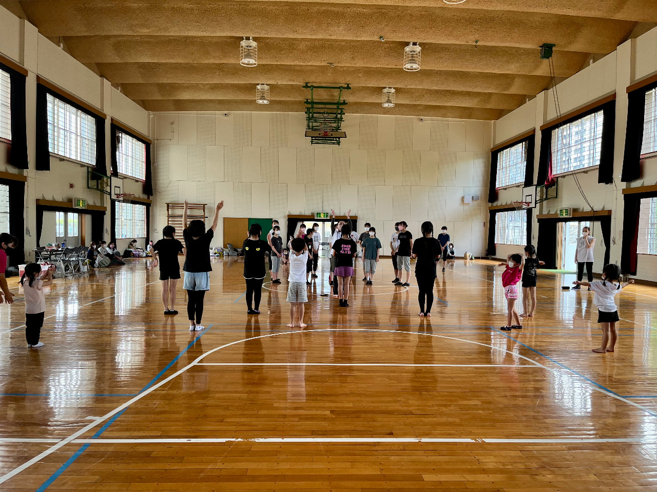 先生が生徒達の中心で両手を挙げ手の振り付けを指導