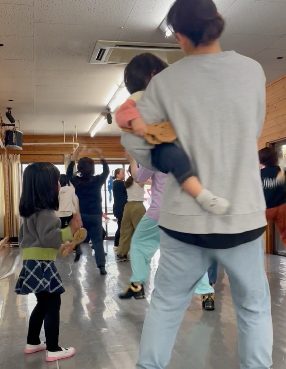 小さな男の子をを抱いたまま踊る母親と隣で踊るお姉ちゃん