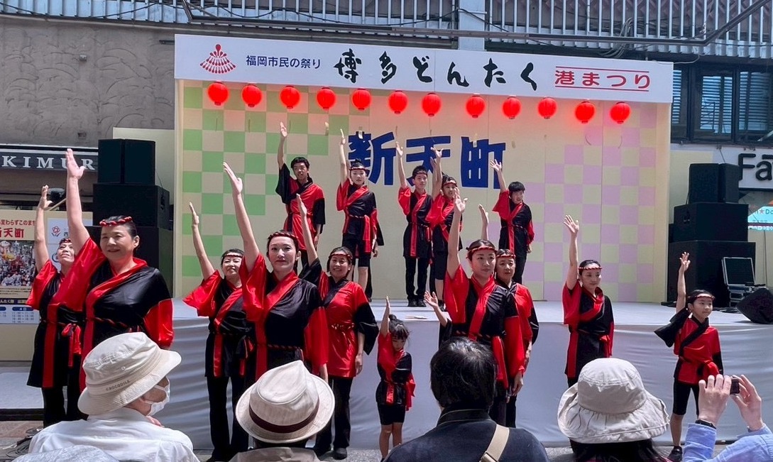 新天町演舞台で全員で手を挙げて観客に挨拶をしている