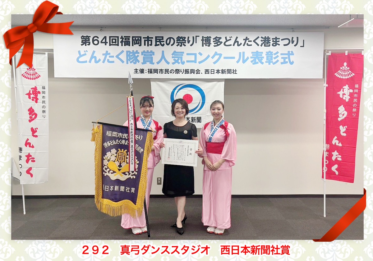 真弓先生を中央にピンクの衣装の着物を着た生徒が二人並んで入賞旗、賞状を持っています